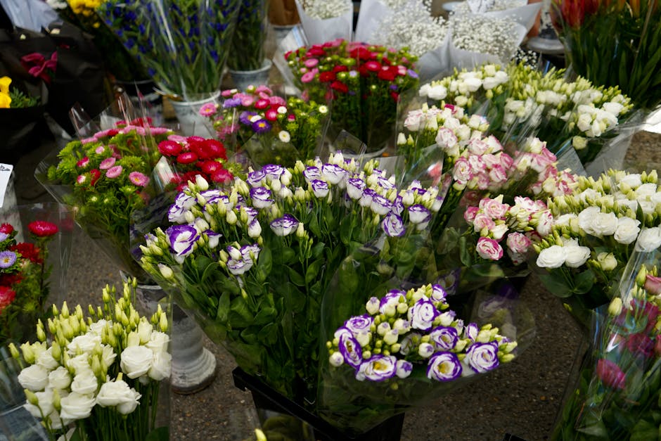 A diverse selection of fresh floral arrangements displayed on a dark countertop, featuring vibrant bouquets of purple and white eustoma (lisianthus), bright pink and red chrysanthemums, and delicate w
