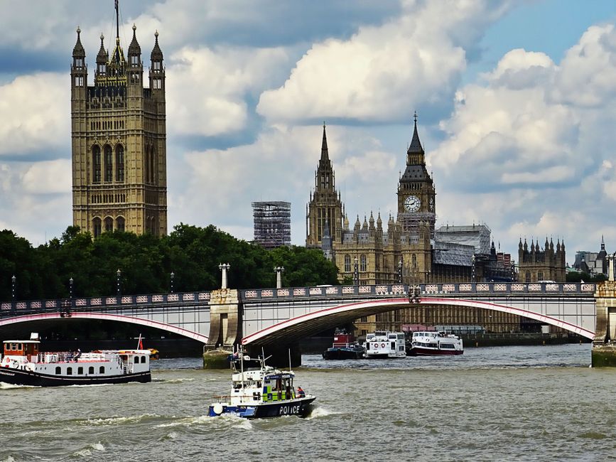 A floral arrangement featuring a bouquet of fresh flowers held in hands, with a backdrop of Westminster Bridge over the River Thames and iconic landmarks such as the Houses of Parliament and Big Ben u